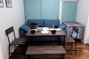 A dining area with a wooden table, blue sofa, and chairs. - Korean Town Front/ Sleeps 8/ 9 Min Walk to Tsuruhashi St/ Direct Access to Namba (Osaka)