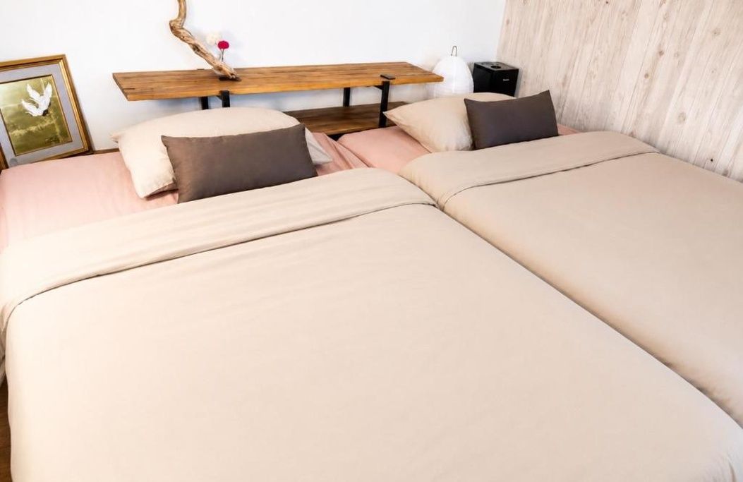 Cama doble con cabecera de madera, mesita de noche y un cuadro enmarcado en la pared.