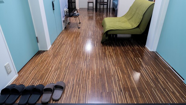A room with a wooden floor, a green chair, a table, and a pair of slippers. - Korean Town Front/ Sleeps 8/ 9 Min Walk to Tsuruhashi St/ Direct Access to Namba (Osaka)