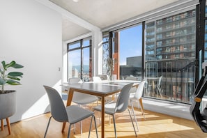 A modern dining area with a large table, chairs, and a potted plant.