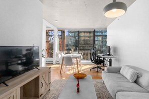 Ein modernes Wohnzimmer mit Fernseher, Sofa, Esstisch und Stühlen.