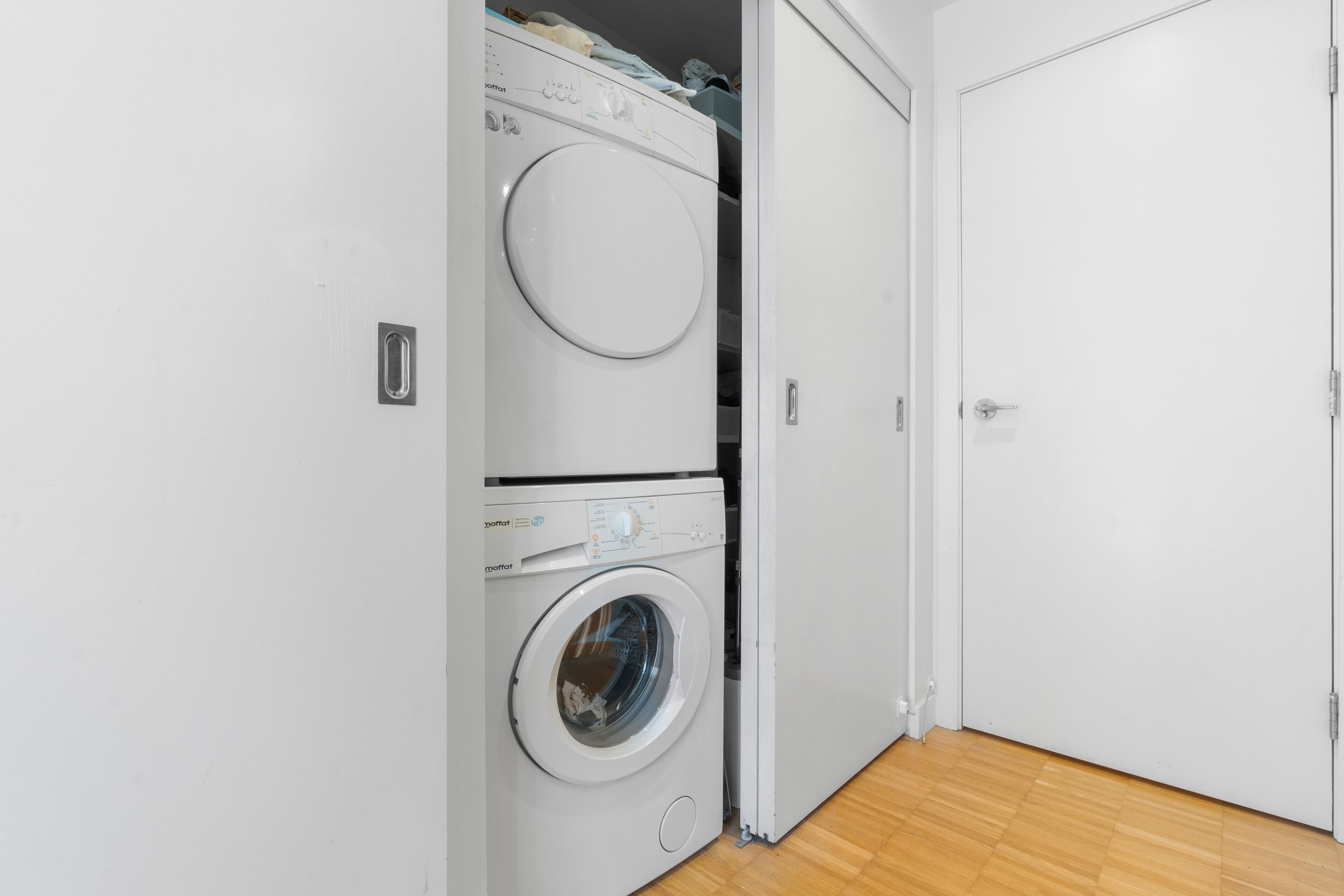 A laundry room with stacked washing machines and a closed door.