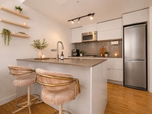 A modern kitchen with a central island, stainless steel appliances, and a bar stool seating area.