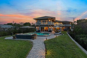 Ein zweistöckiges Haus mit Swimmingpool, Außenbereich und einem gepflegten Rasen.