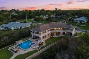 Ein geräumiges Haus mit Pool, mehreren Terrassen und einem gepflegten Rasen.