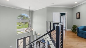 Un interior moderno con una escalera, un sofá azul y vistas al exterior.