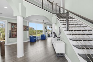 Ein großzügiger Wohnbereich mit Treppe, großem Fenster und Deckenventilator.