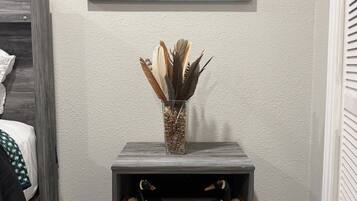 A room with a bed, a nightstand with a vase, and a painting on the wall.