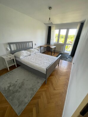 Un dormitorio con cama, mesita de noche, lámpara y vistas al exterior a través de una ventana.