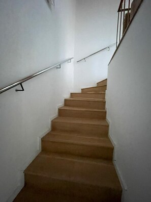 Una escalera con escalones de madera y barandillas de metal, que sube.