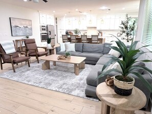 A modern living room with a sectional sofa, a coffee table, and a dining area with chairs.