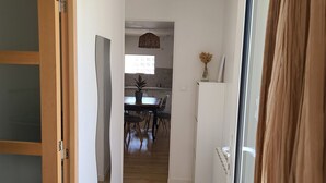A hallway leading to a dining area with a table and chairs, a hanging light fixture, and a potted plant. - Charming town house, 10min walk to the beach (saint gildas de rhuys)