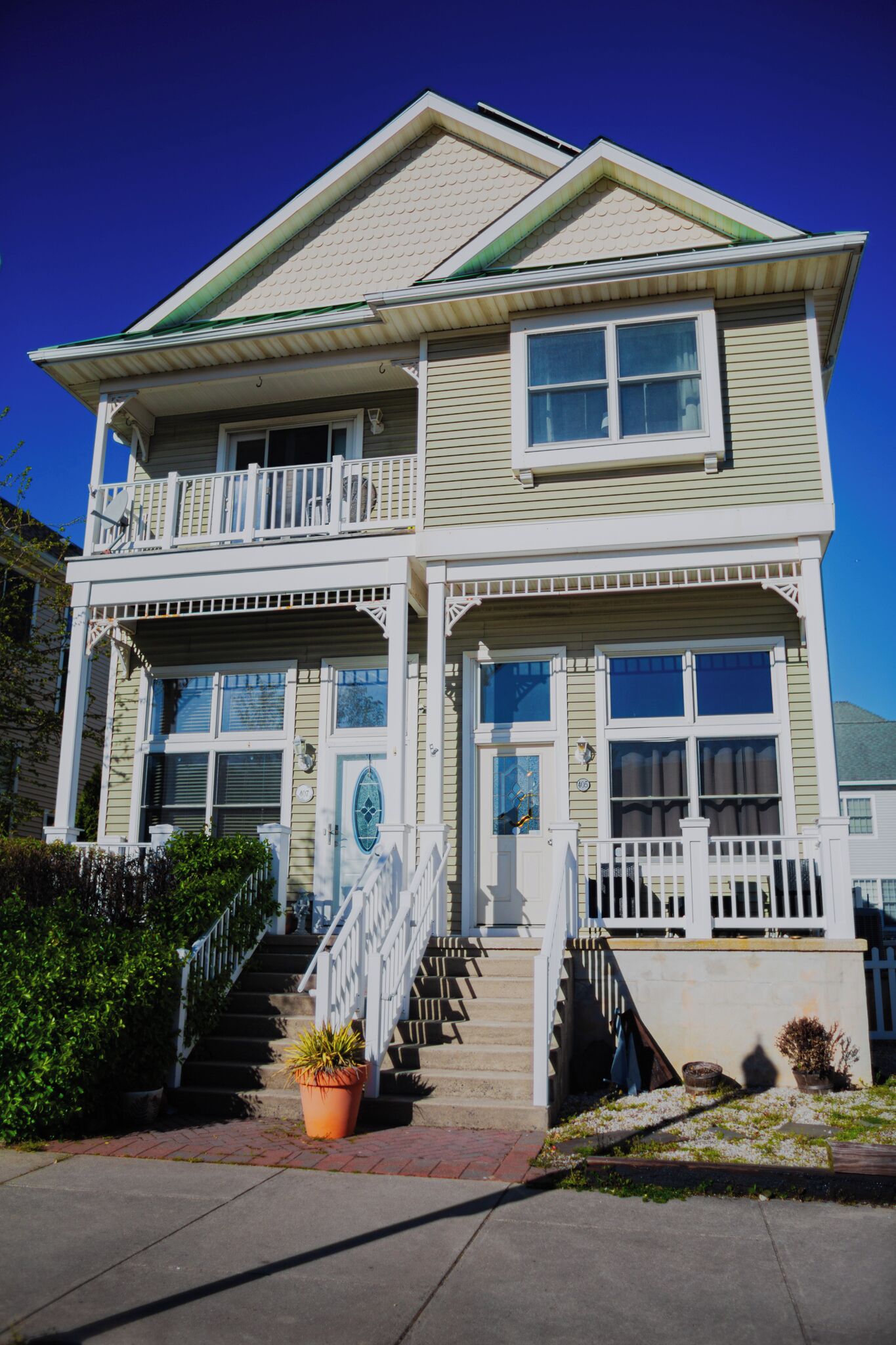 A two-story house with a balcony, a front porch, and a staircase leading to the entrance.