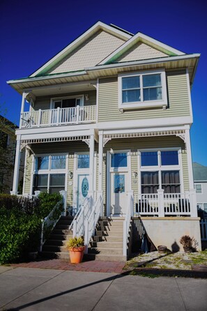 A two-story house with a balcony, a front porch, and a staircase leading to the entrance.