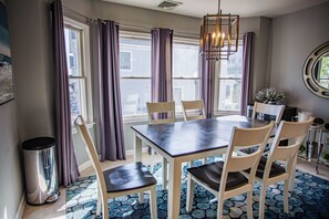 A dining area with a table, chairs, a trash can, and a patterned floor.