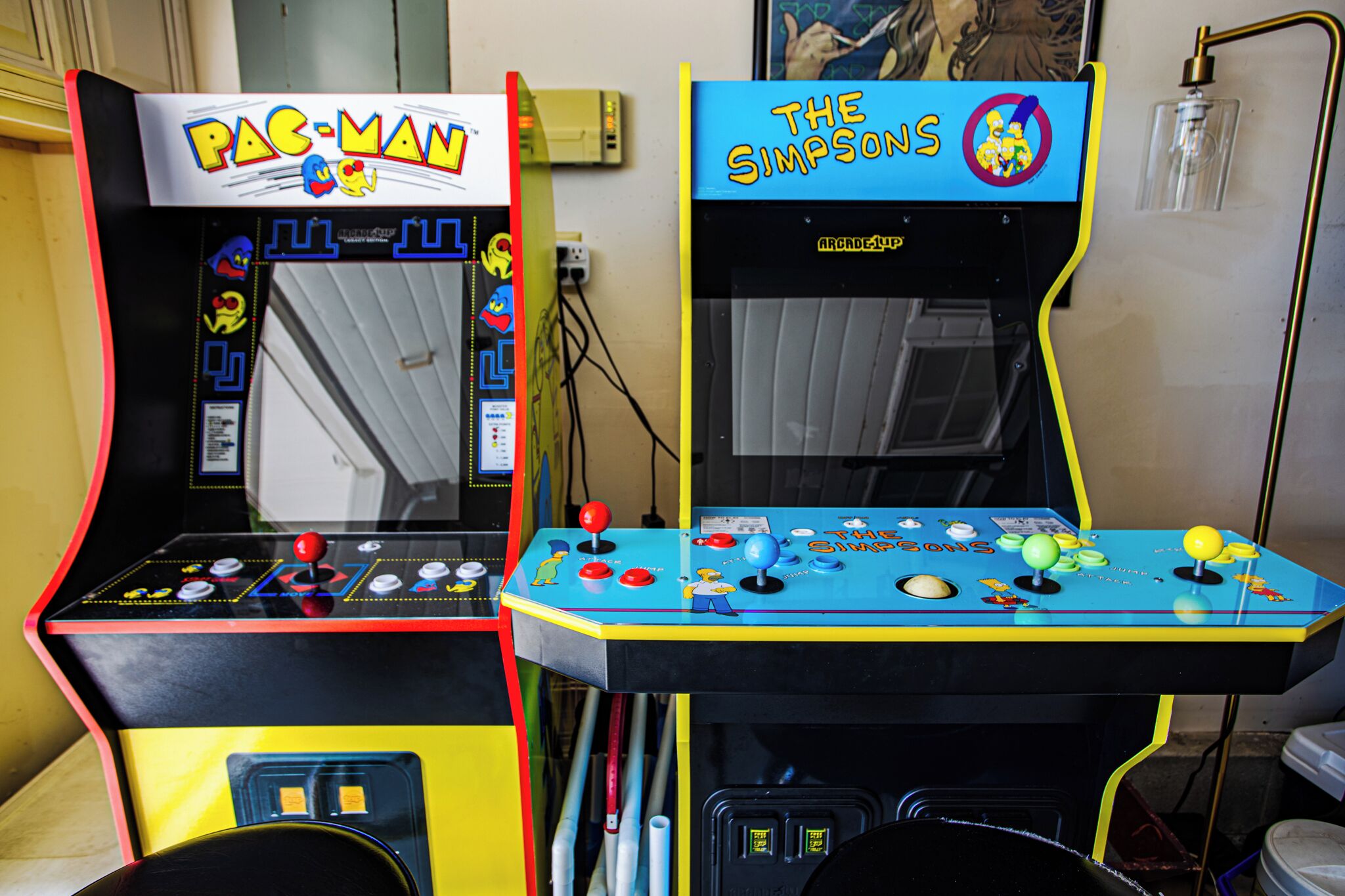 Two arcade machines, one labeled 'Pac-Man' and the other 'The Simpsons,' with control panels and game characters.