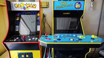 Two arcade machines, one labeled 'Pac-Man' and the other 'The Simpsons,' with control panels and game characters.