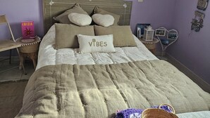 A bedroom with a bed, pillows, a bedside table, a chair, a wall decoration, and a hanging light fixture. - Cosy interlude at Anastasia's sunny home in the South of France (Bagnols-sur-Cèze)