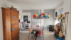 A dining area with a table set for four, a wooden cabinet, and a colorful parrot mural on the wall. - Cosy interlude at Anastasia's sunny home in the South of France (Bagnols-sur-Cèze)