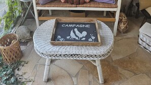 A rustic wooden bench with a cushion, a small table with a 'CAMPAGNE' sign, and a window with butterfly decorations. - Cosy interlude at Anastasia's sunny home in the South of France (Bagnols-sur-Cèze)