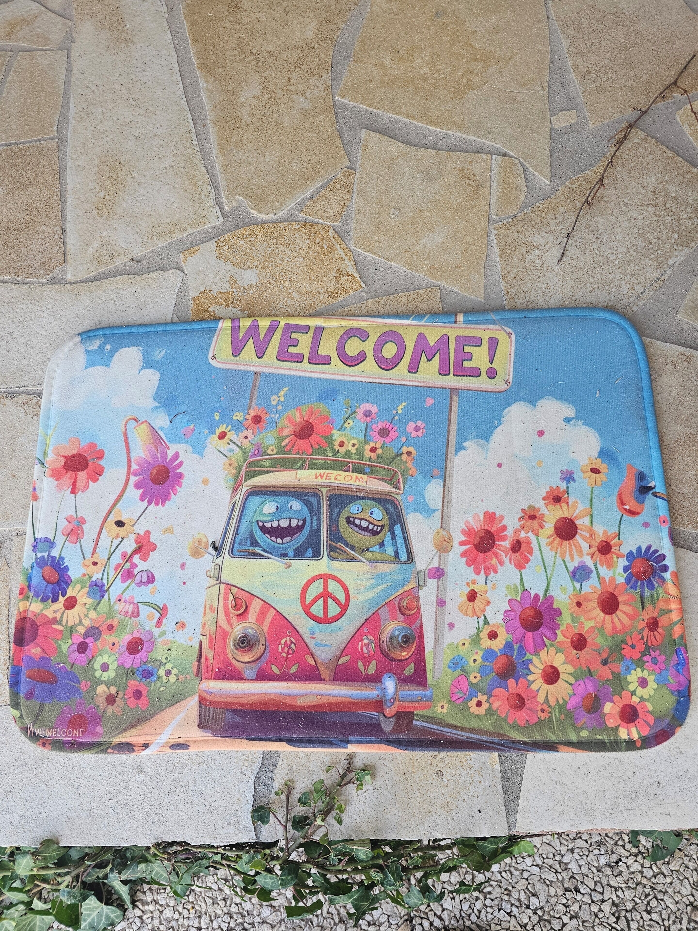 A colorful welcome mat with a van and flowers.