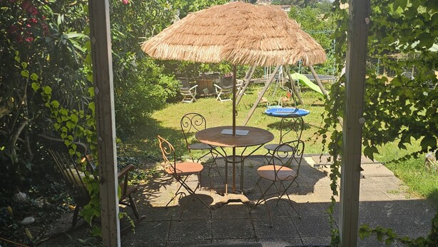 A patio area with a thatched umbrella, outdoor seating, and a welcome mat. - Cosy interlude at Anastasia's sunny home in the South of France (Bagnols-sur-Cèze)