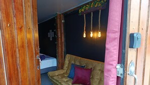 A room with a wooden door, a sofa with cushions, a bed, and a wall-mounted light fixture. - Private room with independent entrance (Salento)