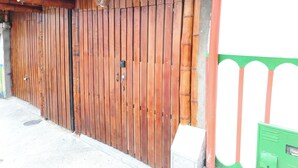 A large wooden gate with a metal handle and a keyhole, attached to a building with a green and white wall. - Private room with independent entrance (Salento)