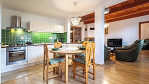 A modern kitchen with white cabinets, a green backsplash, and a dining area with wooden chairs and a table. - Pet-Friendly Family House with Garden near Piešťany Spa Town (Brunovce)