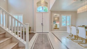 A spacious interior with a staircase, a white door, and a dining area with chairs. - Elegant 5BR Gem @Ontario w/ Grill | Near Airport (Ontario)