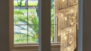 A view through a window with a decorative hanging light fixture. - Elegant 5BR Gem @Ontario w/ Grill | Near Airport (Ontario)