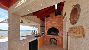 Eine Küche mit Backofen, Steinwänden und Blick aufs Meer.