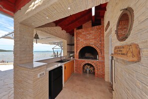 Eine Küche mit Backofen, Steinwänden und Blick aufs Meer.