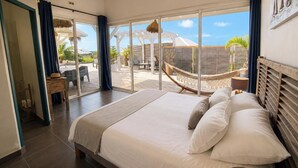 A bedroom with a large bed, a view of the outdoor area, and a hammock. - Villa Ouassou, sea view and swimming pool between Gosier and St Anne (st anne)
