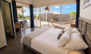 A bedroom with a large bed, a view of the outdoor area, and a hammock. - Villa Ouassou, sea view and swimming pool between Gosier and St Anne (st anne)