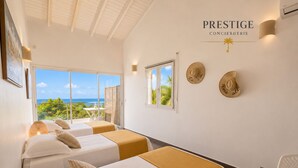 A hotel room with two beds, a balcony with a view, and a sign reading 'PRESTIGE CONCIERIE'. - Villa Ouassou, sea view and swimming pool between Gosier and St Anne (st anne)