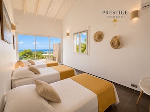 A hotel room with two beds, a balcony with a view, and a sign reading 'PRESTIGE CONCIERIE'. - Villa Ouassou, sea view and swimming pool between Gosier and St Anne (st anne)