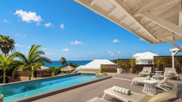 A poolside area with lounge chairs, a wooden deck, and a view of the ocean. - Villa Ouassou, sea view and swimming pool between Gosier and St Anne (st anne)