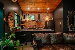 A modern kitchen with a brick wall, wooden ceiling, and hanging pendant lights.