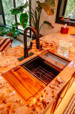 A kitchen with a marble countertop, a built-in sink, and a wooden drawer.