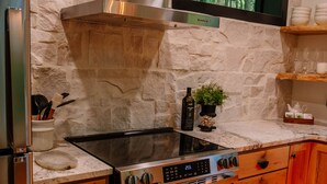 Uma cozinha com fogão, forno e uma parede de pedra.