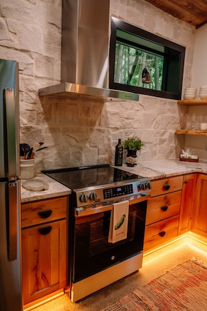 A kitchen with a stove, oven, and a stone wall.