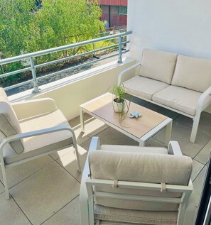 Ein Balkon mit einer Couch, Stühlen, einem Tisch und Geländer.