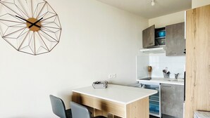 A modern kitchen with a wooden island, a dining area with two chairs, and a grey sofa. - T1 bis - Quiet in La Rochelle (La Rochelle)
