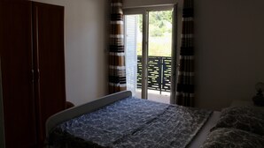 Ein Schlafzimmer mit einem Bett, einem Kleiderschrank und einem Balkon mit Vorhängen.