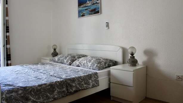 Ein Schlafzimmer mit einem Bett, Nachttischen, einer Wandklimaanlage, einem Bild und einer Steckdose.