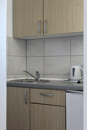 A kitchen with wooden cabinets, a stainless steel sink, and a kettle. - One Bedroom Apartment with Balcony and Mountain View (Baška Voda)
