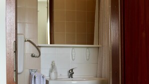 Et badeværelse med toilet, vask og spejl.