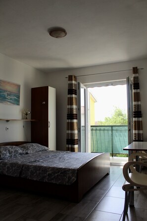 Ein Schlafzimmer mit Bett, Kleiderschrank, einem kleinen Tisch und Blick durch eine Schiebetür.