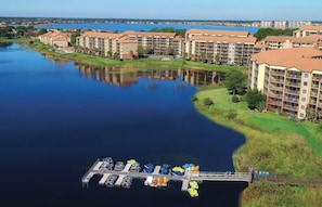 A waterfront hotel with multiple buildings, a dock with boats, and a calm river.